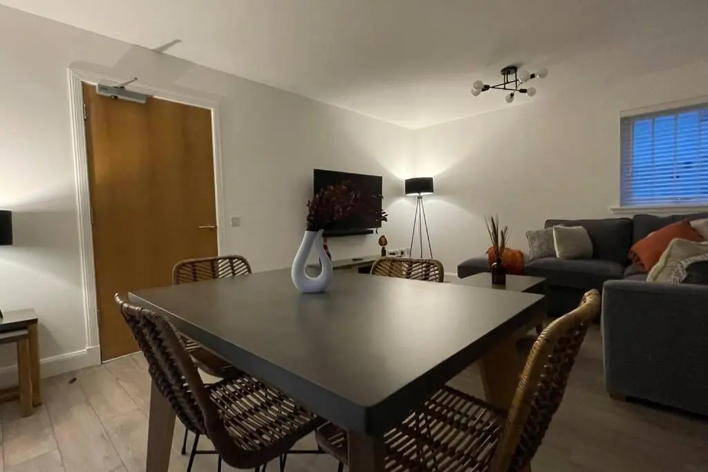 a living room with a table with chairs and a couch at Harbourside by Caithness Luxury Apartments NC500 - 2 Bedroom holiday home - Sleeps Work teams upto 2 & holiday makers upto 6 with bike store in Wick