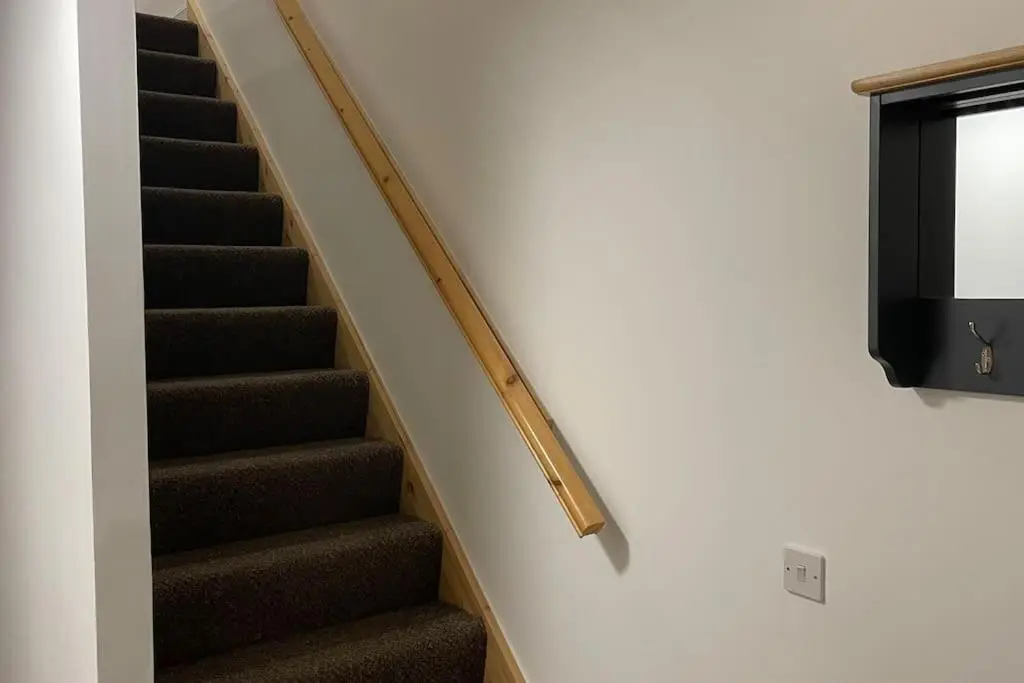 a staircase with a wooden hand rail and a television at Harbourside by Caithness Luxury Apartments NC500 - 2 Bedroom holiday home - Sleeps Work teams upto 2 & holiday makers upto 6 with bike store in Wick