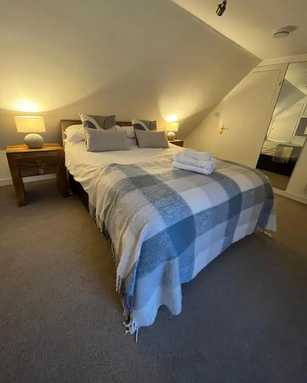 a bedroom with a large bed with a blue and white blanket at North Coast Property - 17 Margaret Street - Avoch in Avoch