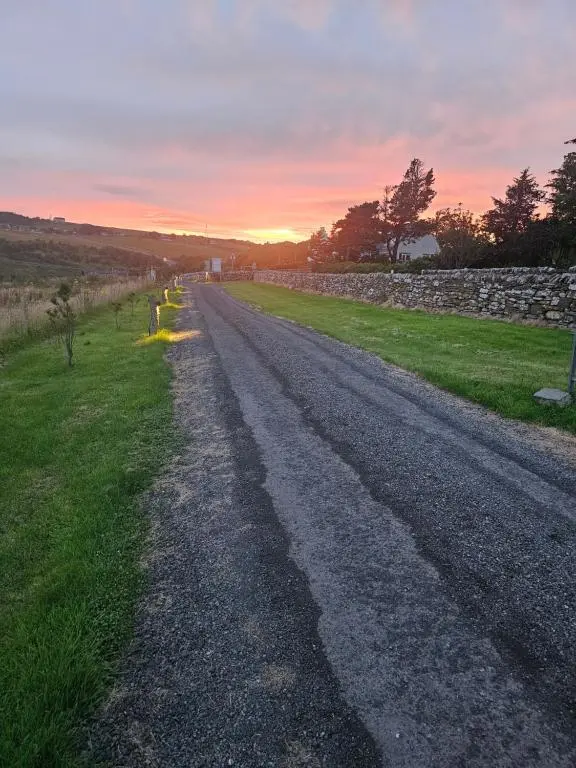 an empty road in a field with a stone wall at Dunbeath Coastal Retreat in Dunbeath