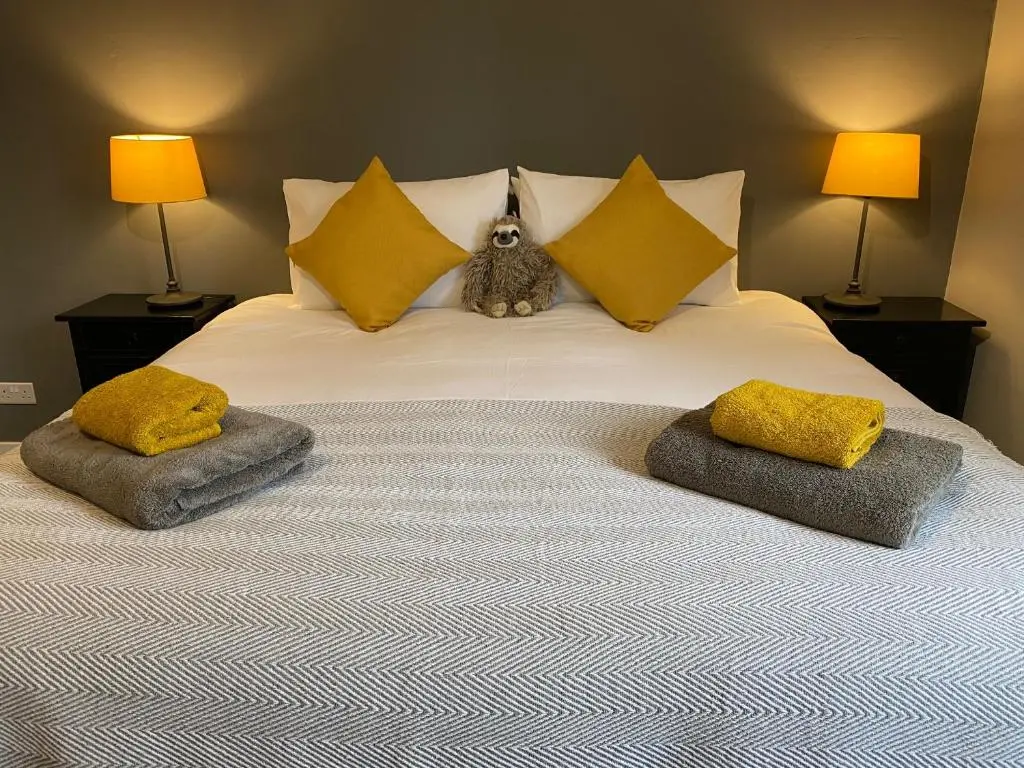 a cat sitting on top of a bed with pillows at Ardenbeg in Grantown on Spey