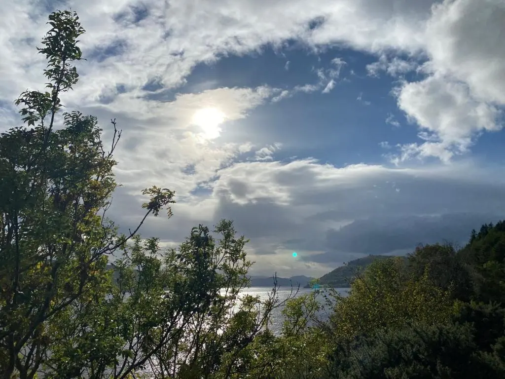 a cloudy sky over a body of water with trees at Ardenbeg in Grantown on Spey