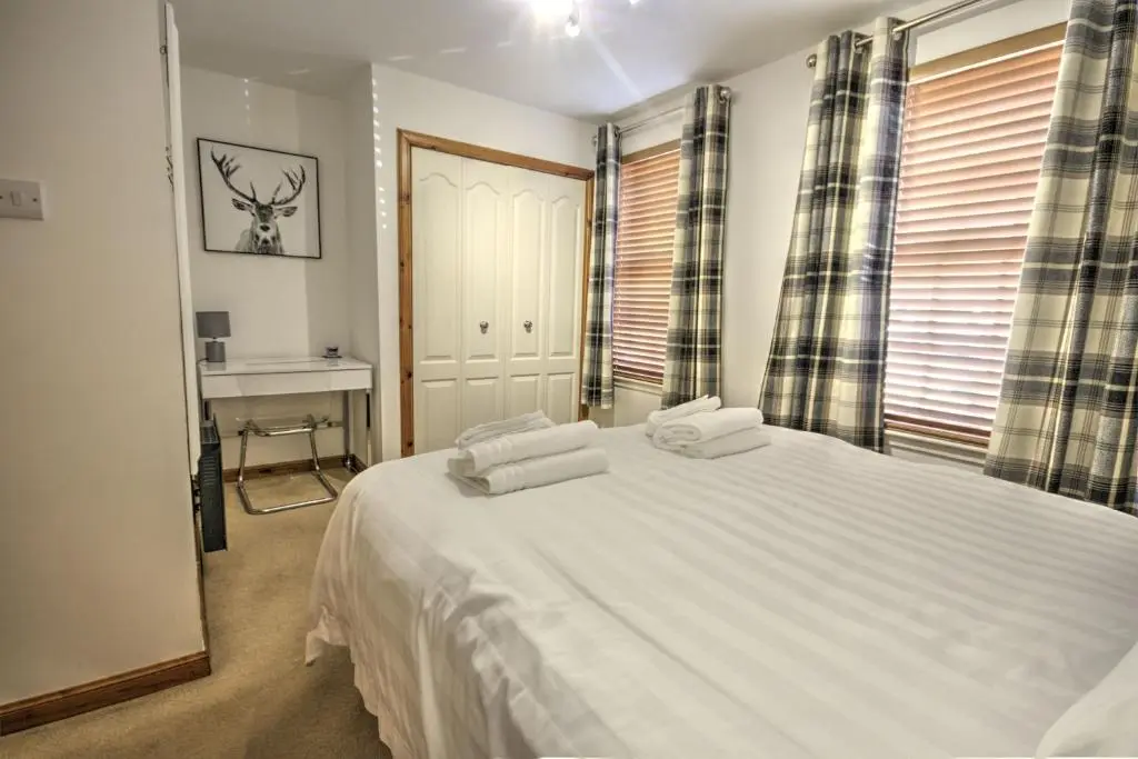 a bedroom with a large white bed and a desk at 5 Argyle Place, Dornoch in Dornoch