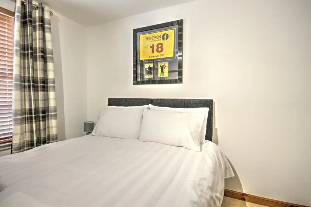 a bedroom with a bed with white sheets at 5 Argyle Place, Dornoch in Dornoch