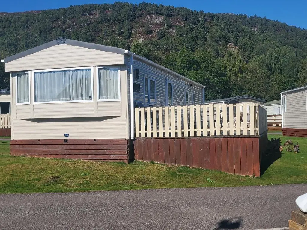 a house with a wooden fence and a fence at Summer Breeze in Aviemore