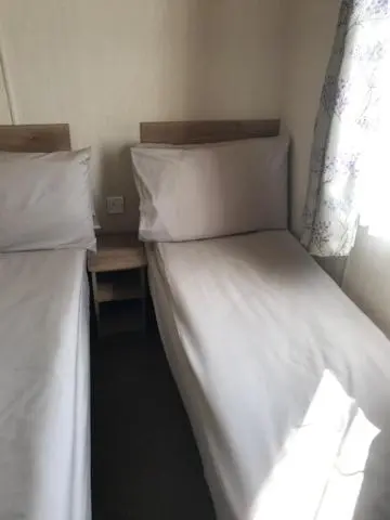 a bedroom with two beds with white sheets and a window at Summer Breeze in Aviemore