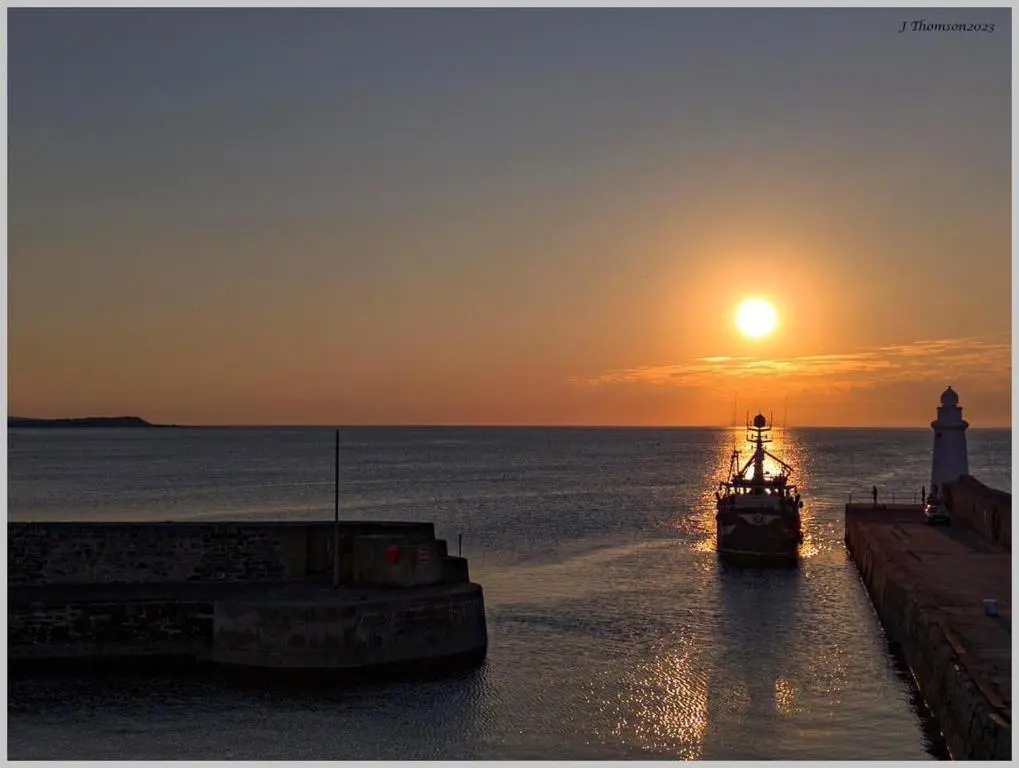 a boat in the water with the sunset in the background at Moray View, Macduff, Aberdeenshire. in Macduff