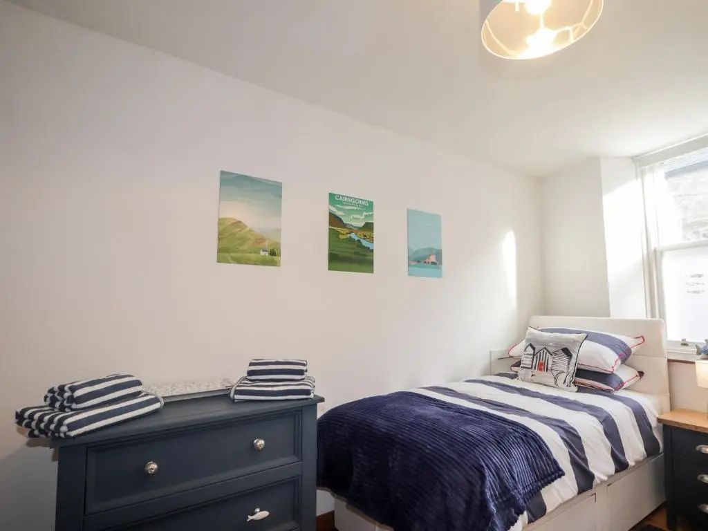 a bedroom with a bed and a blue dresser at 2 Seafield Place in Portsoy