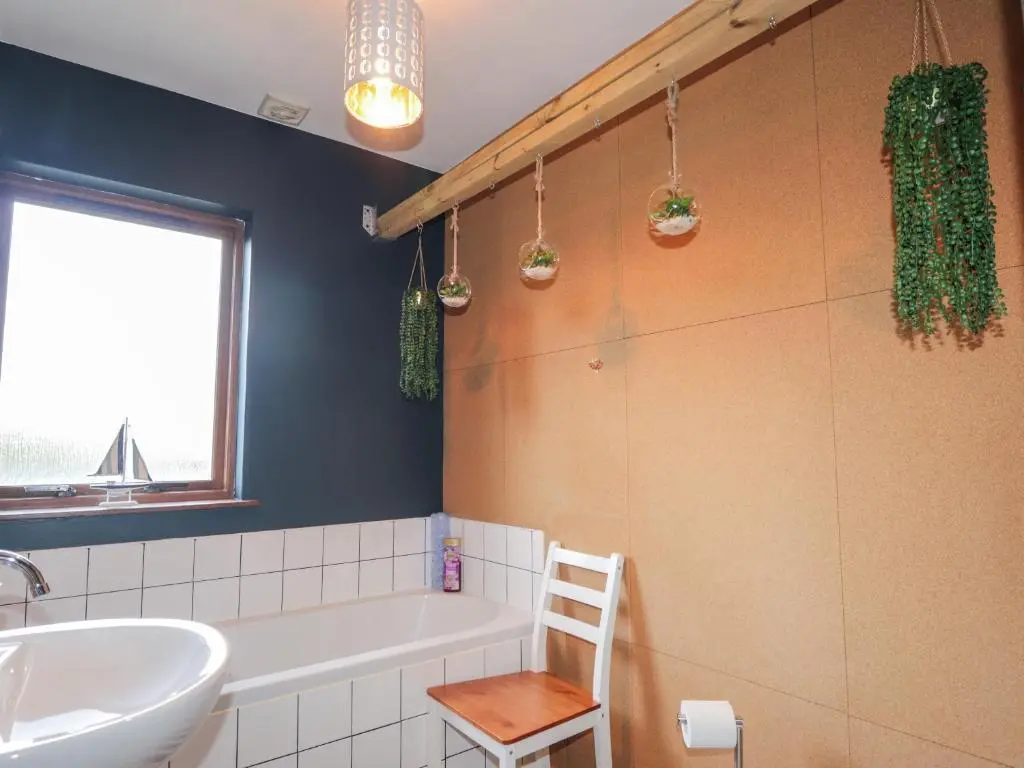 a bathroom with a tub and a sink and a chair at 2 Seafield Place in Portsoy