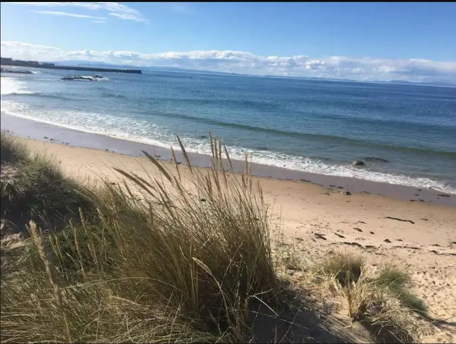 a sandy beach with the ocean in the background at St Marys Farmhouse - Traditional Country Farmhouse with Open Fire in Fochabers