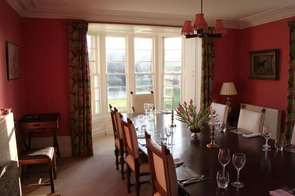 a dining room with a long table and chairs at St Marys Farmhouse - Traditional Country Farmhouse with Open Fire in Fochabers