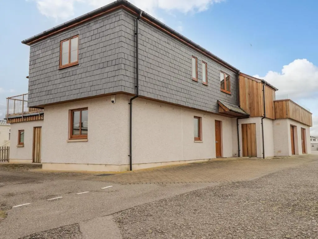 a large white building with a gray roof at Lossiemouth Bay Cottage in Lossiemouth