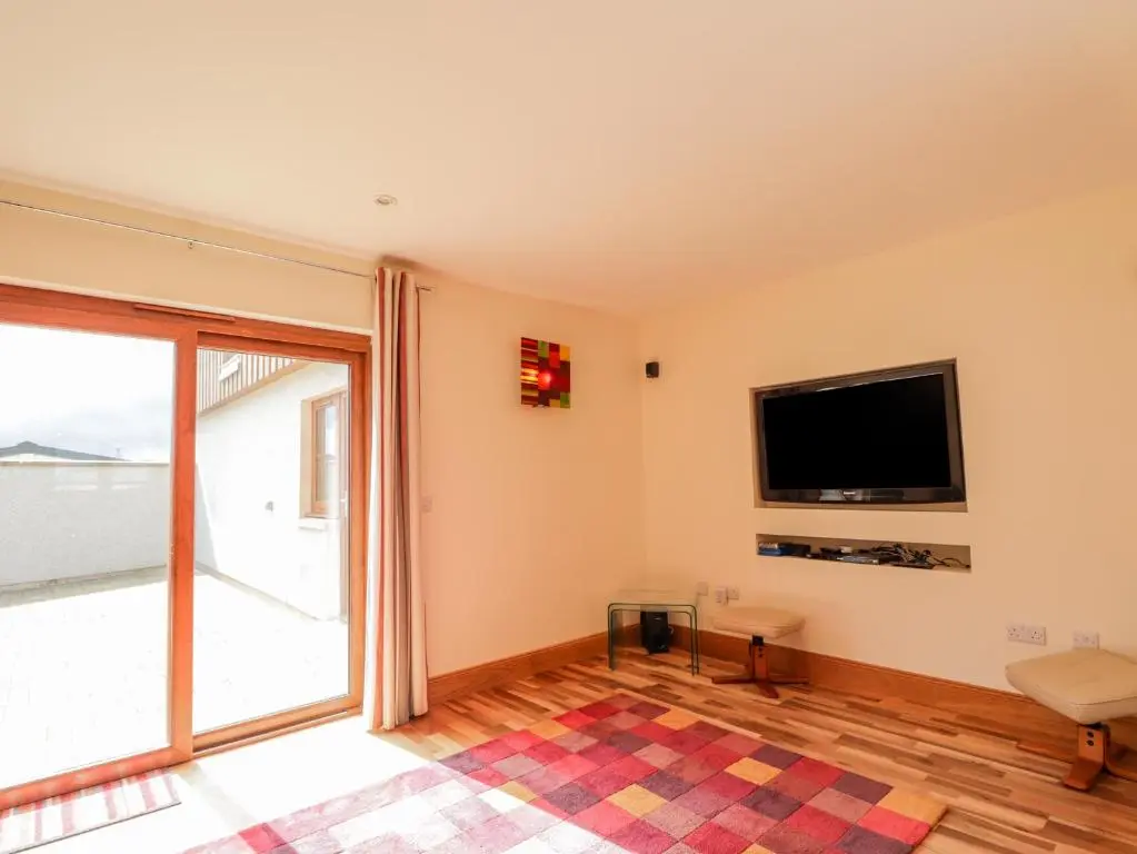 a living room with a tv and a large window at Lossiemouth Bay Cottage in Lossiemouth
