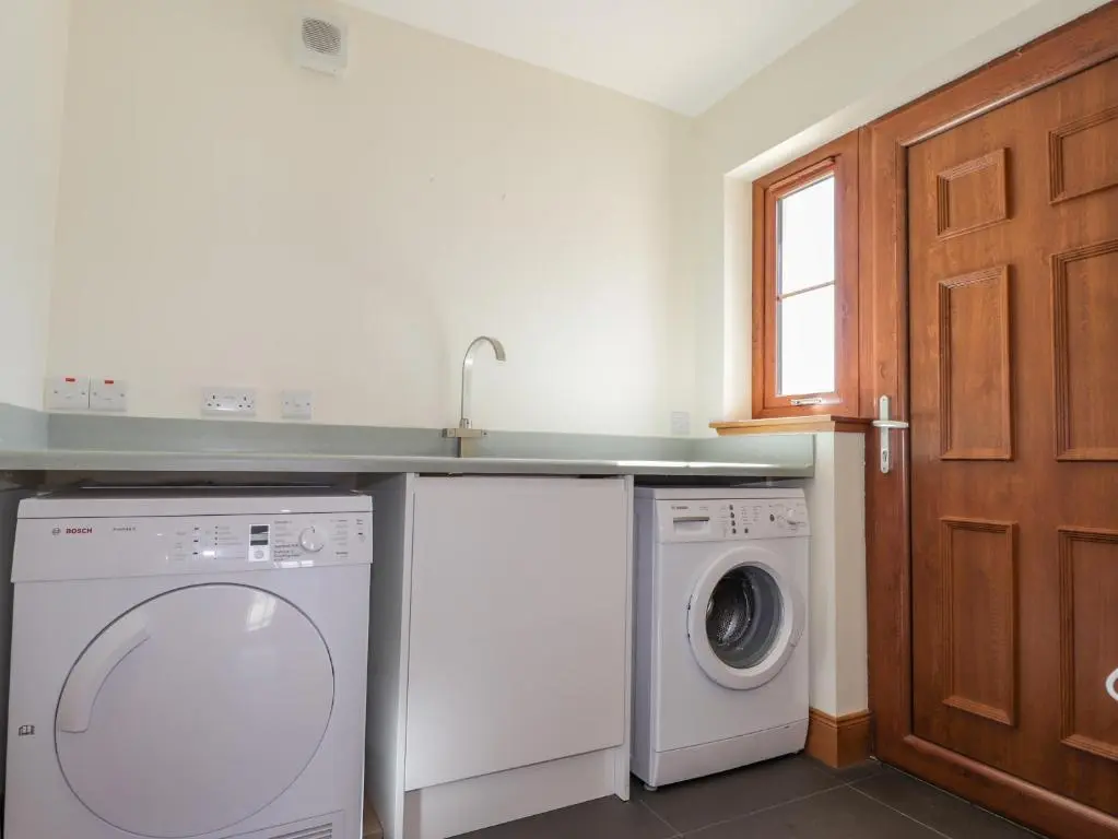 a kitchen with a washing machine and a sink at Lossiemouth Bay Cottage in Lossiemouth