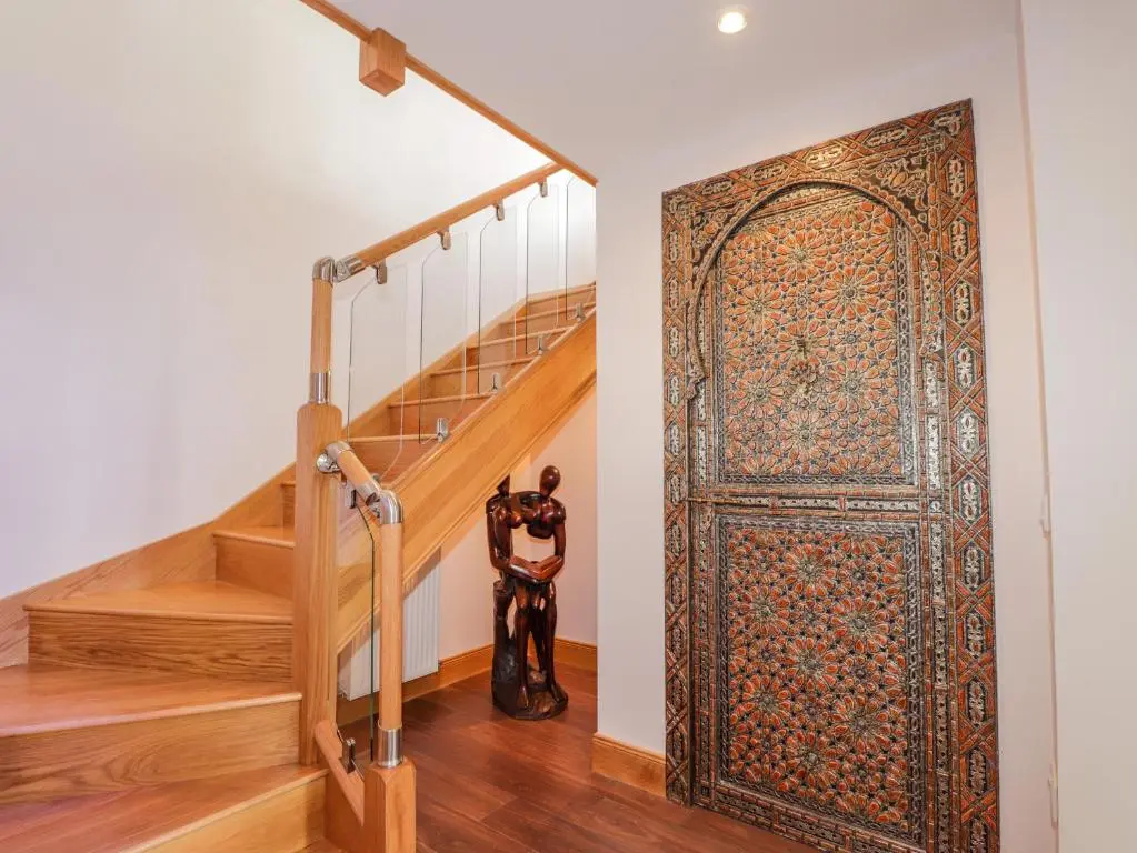 an ornate door in a hallway with stairs at Lossiemouth Bay Cottage in Lossiemouth