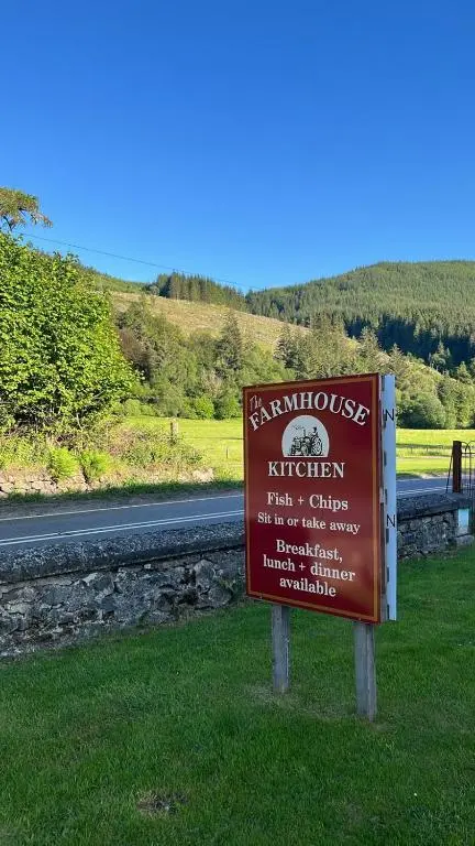 a brown sign in the grass next to a road at Great Glen Hostel in Spean Bridge