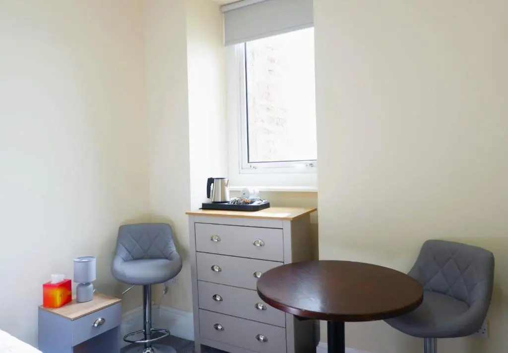 a bedroom with a table and two chairs and a dresser at Jacobite house in Inverness