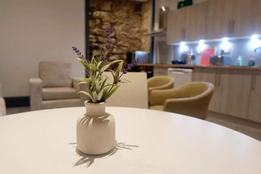 a white vase with purple flowers sitting on a table at Jacobite house in Inverness