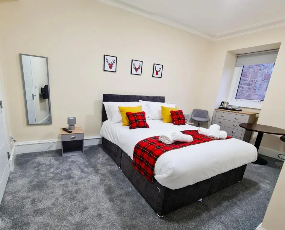 a bedroom with a large bed with red and yellow pillows at Jacobite house in Inverness