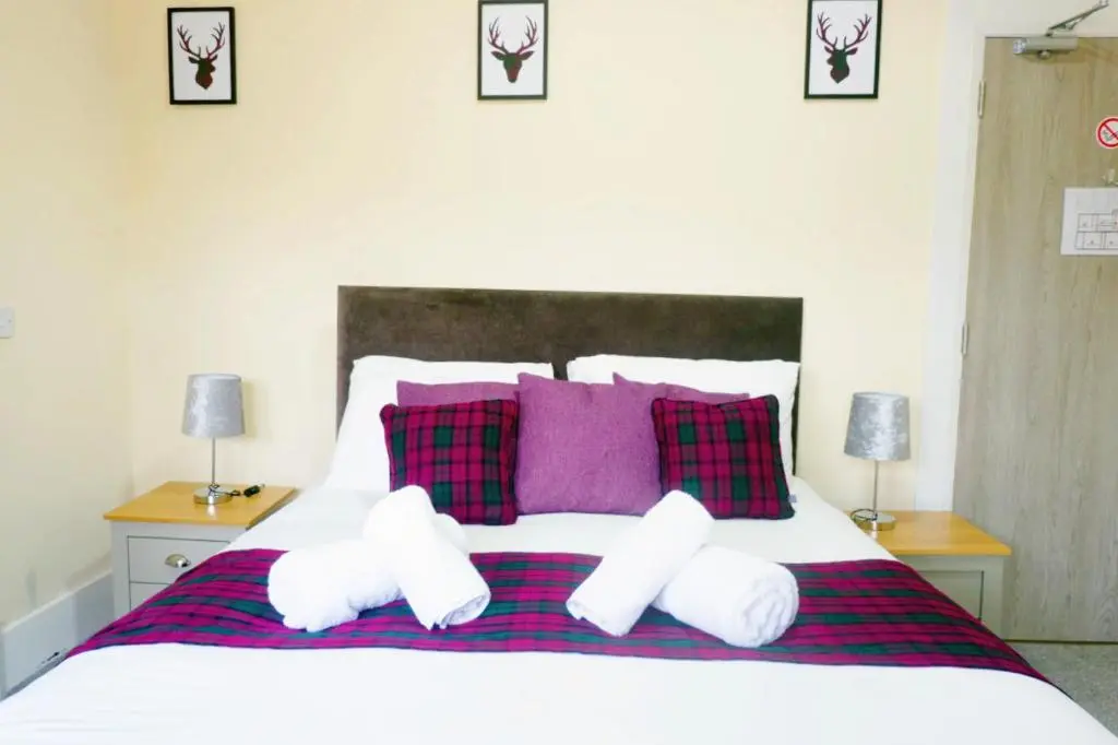 a bedroom with a large bed with purple pillows at Jacobite house in Inverness