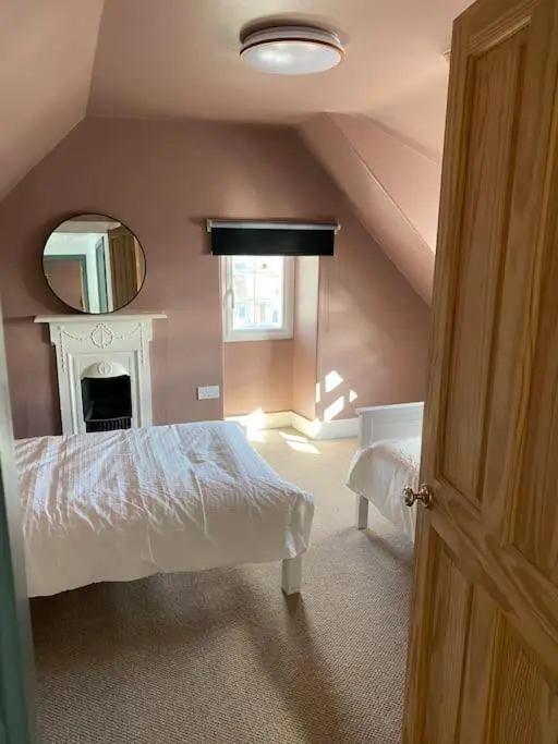 a bedroom with a white bed and a mirror at Frasers Apartment in Golspie