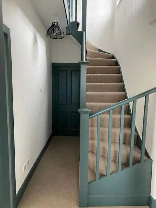 a stairway with a blue door and a stair case at Frasers Apartment in Golspie