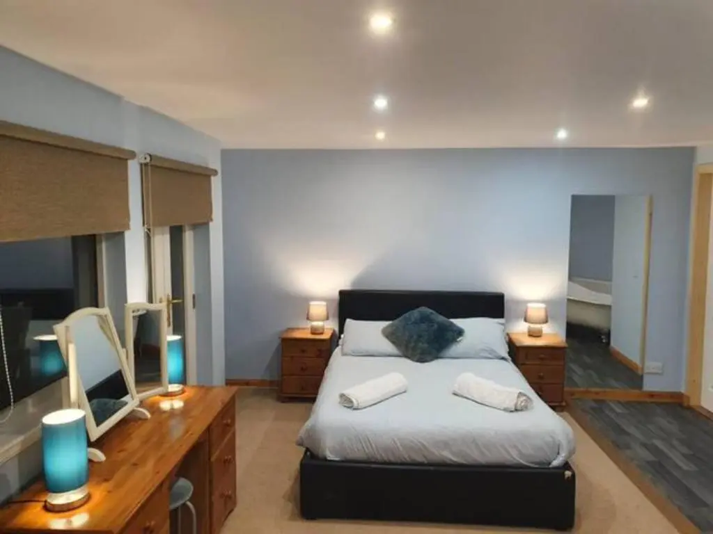 a bedroom with a bed and a desk with a mirror at Ensuite Rooms in Wick