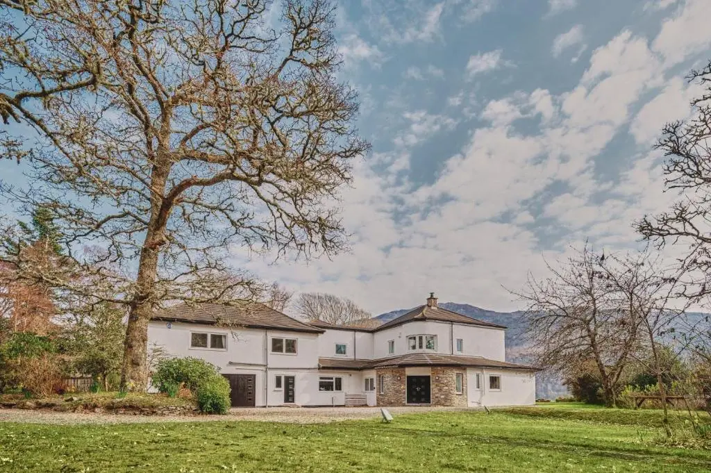 a large white house with a tree in the yard at Loch Ness Mansion in Invermoriston