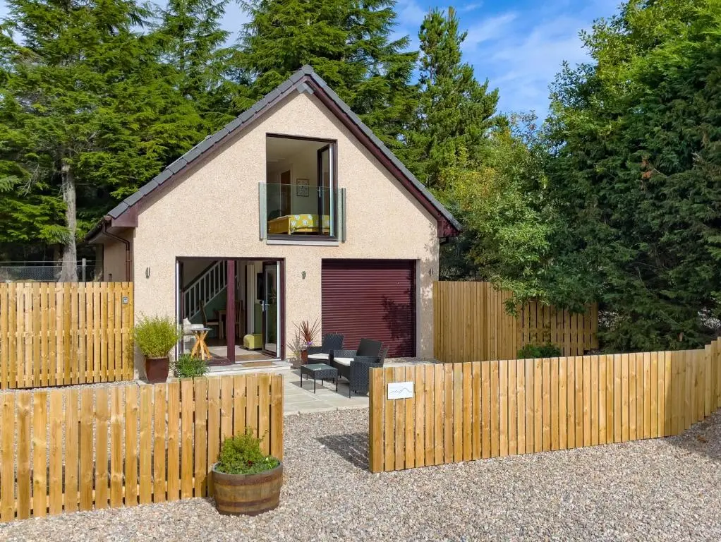 a house with a wooden fence in front of it at Taighsona Bothy, Speyside - amazing views! in Archiestown