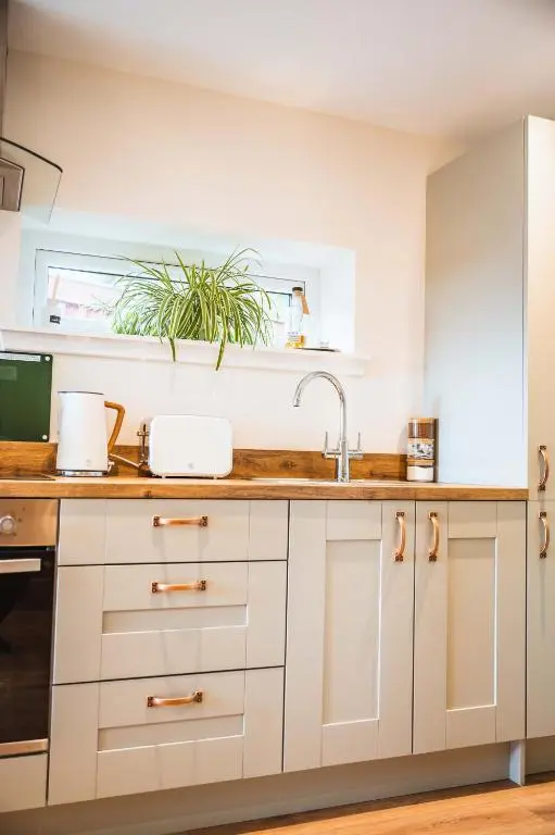 a kitchen with white cabinets and a sink at Taighsona Bothy, Speyside - amazing views! in Archiestown