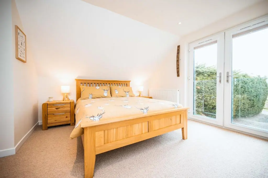 a bedroom with a large bed and a large window at Taighsona Bothy, Speyside - amazing views! in Archiestown