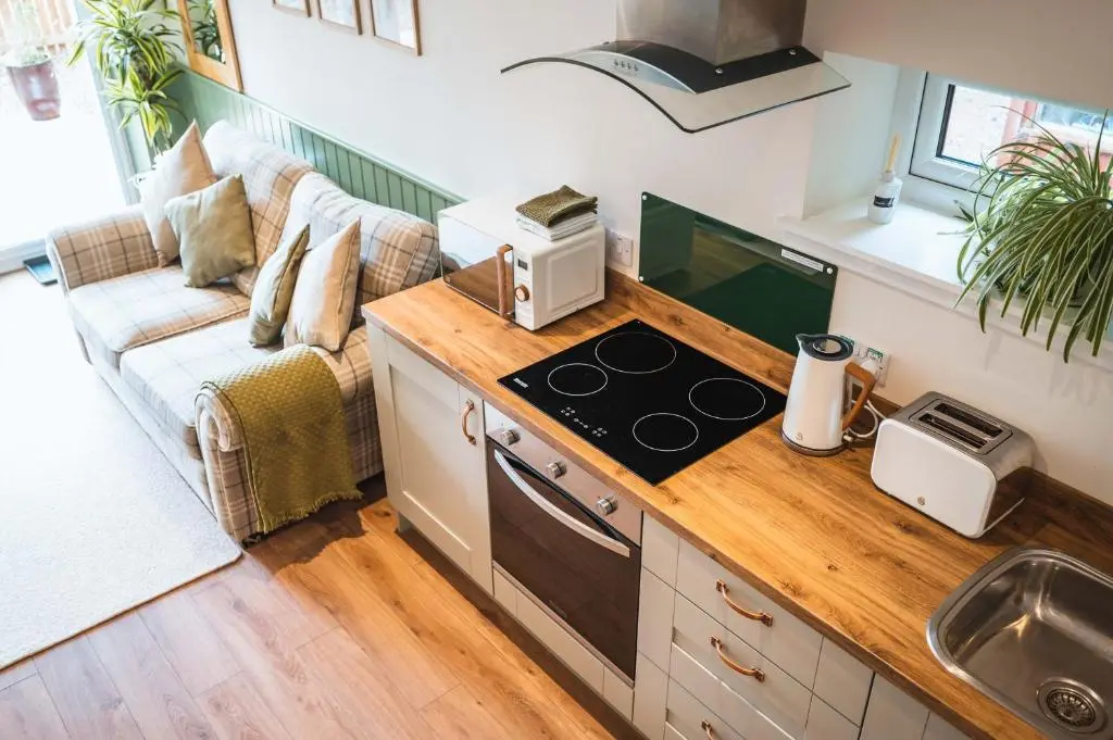 a kitchen with a stove top oven next to a couch at Taighsona Bothy, Speyside - amazing views! in Archiestown