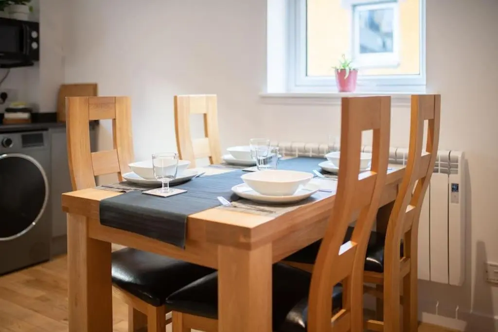 a wooden table with chairs and plates and wine glasses at Modern City Centre Apartment in Inverness in Inverness