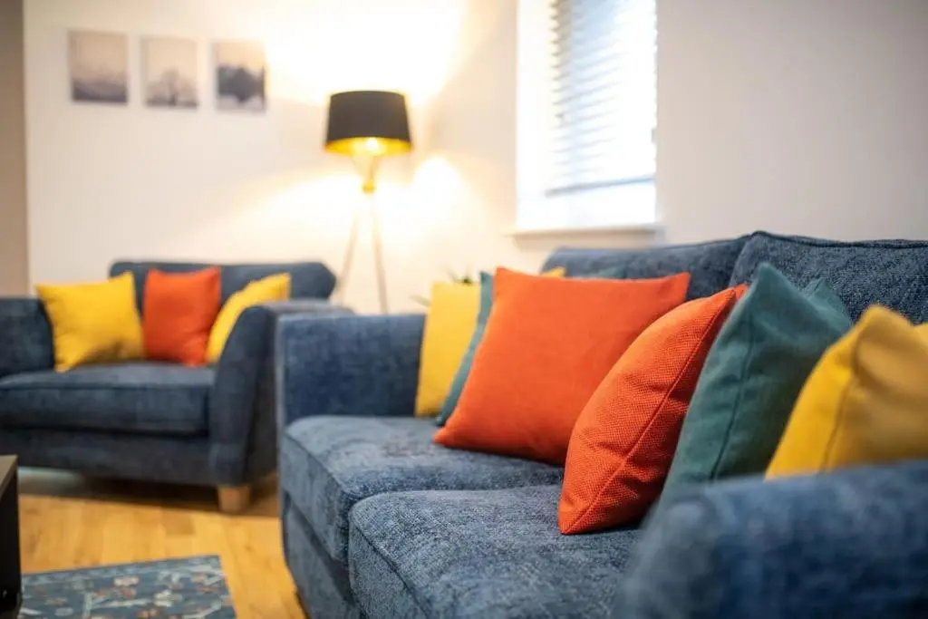 a living room with two blue couches with colorful pillows at Modern City Centre Apartment in Inverness in Inverness