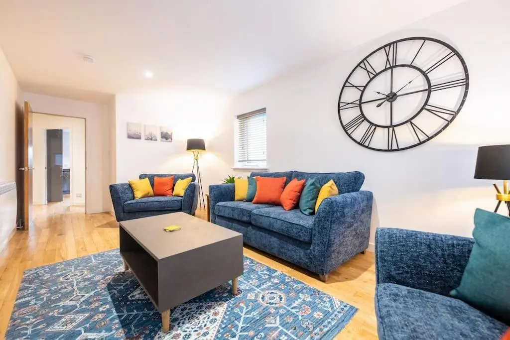 a living room with two blue couches and a clock at Modern City Centre Apartment in Inverness in Inverness