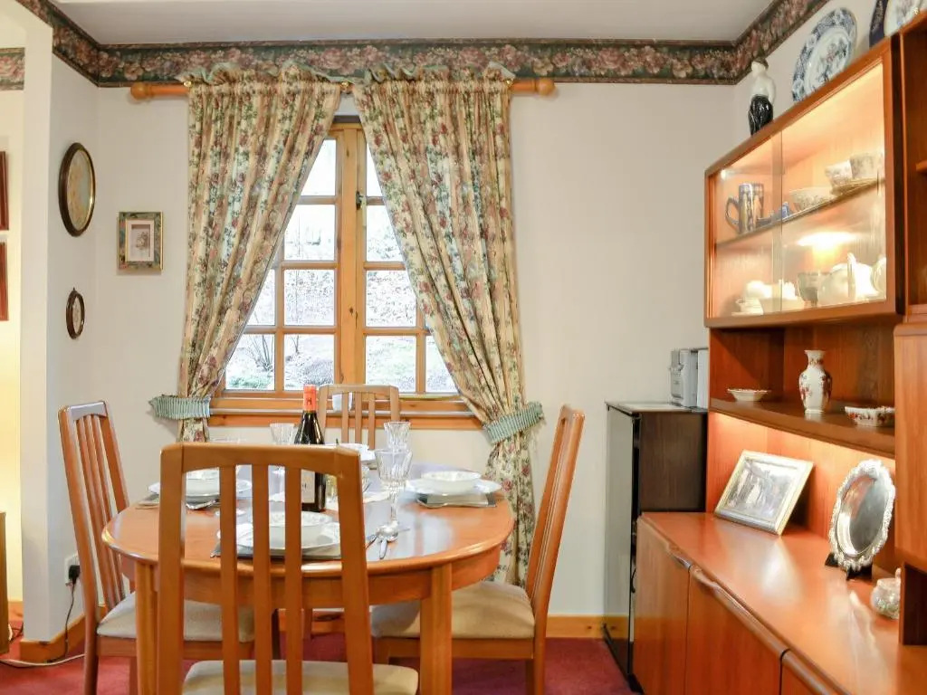 a dining room with a table and a window at Toll Bridge Lodge in Banchory