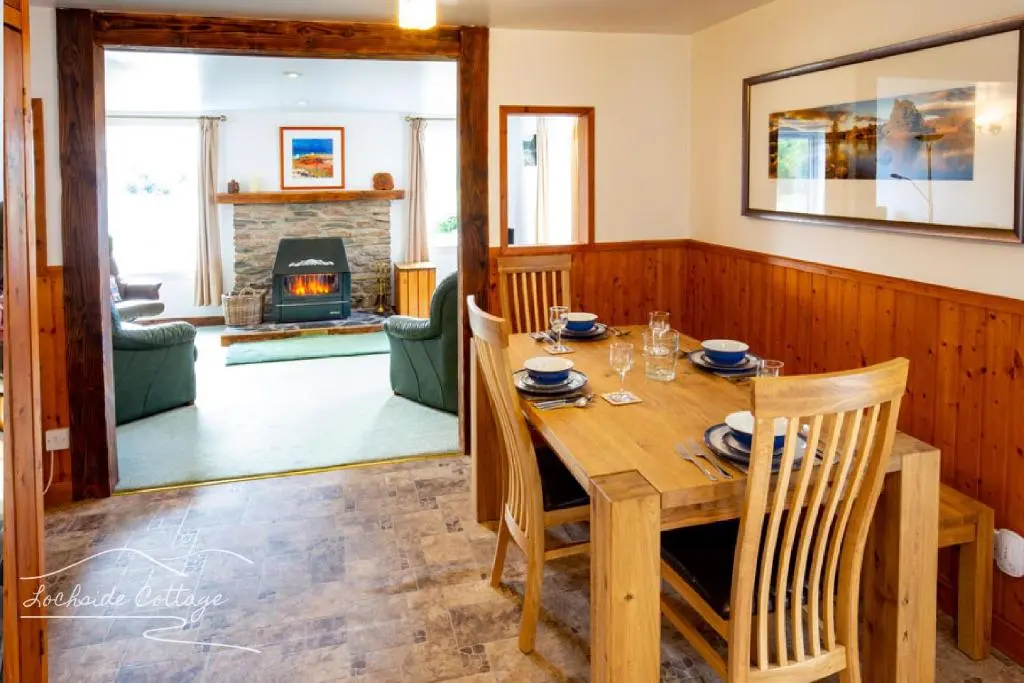 a dining room with a table and a fireplace at Lochside Cottage - near Aviemore in Aviemore