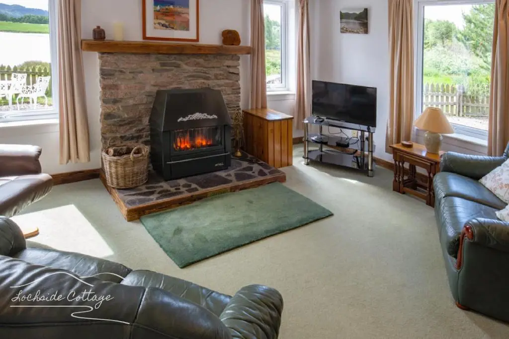 a living room with a fireplace and a couch at Lochside Cottage - near Aviemore in Aviemore