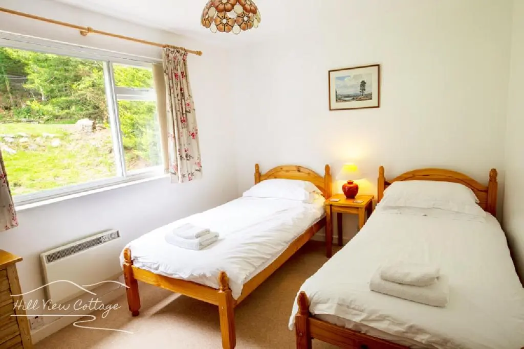 two twin beds in a room with a window at Hill View Cottage - near Aviemore in Aviemore
