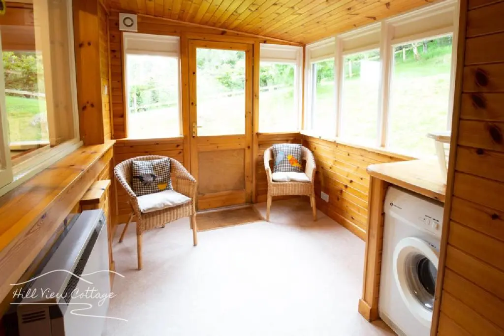 a small room with two chairs and a washing machine at Hill View Cottage - near Aviemore in Aviemore