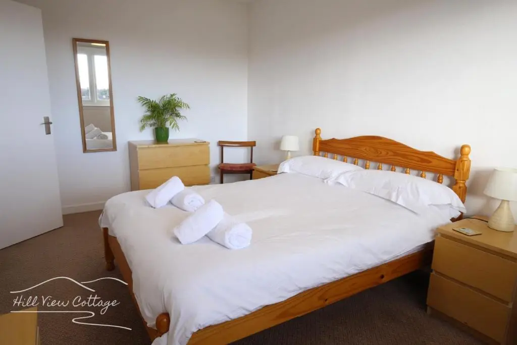 a bedroom with a bed with white sheets and pillows at Hill View Cottage - near Aviemore in Aviemore