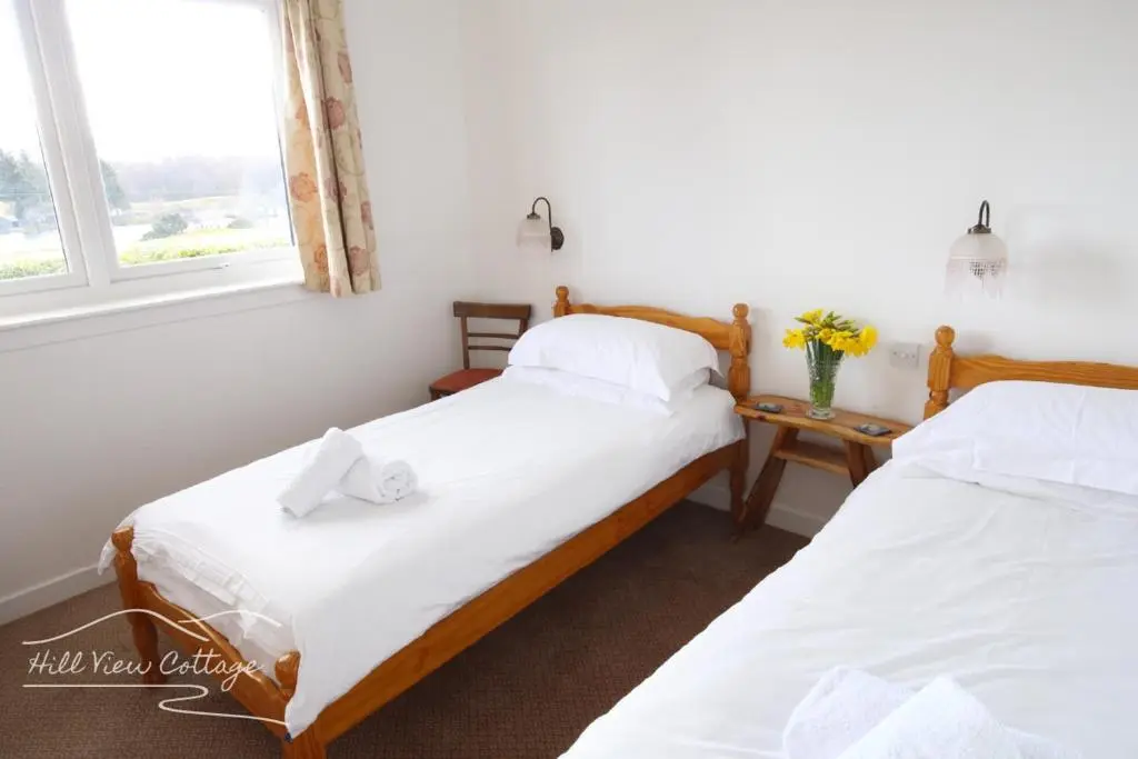 two twin beds in a room with a window at Hill View Cottage - near Aviemore in Aviemore