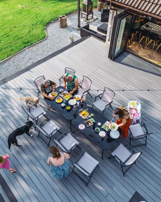 a group of people sitting at a table with a dog at FAMILY FRIENDLY, HOT TUB, Fire Pit, Spacious & Modern in Fochabers