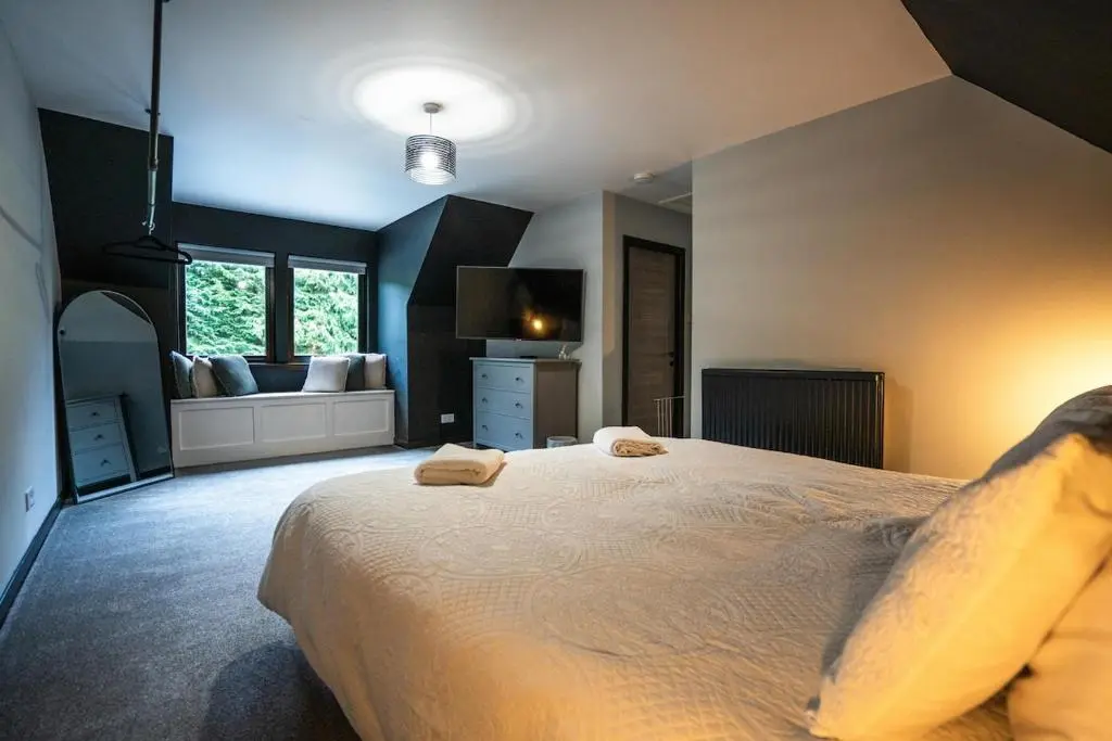 a bedroom with a large bed and a couch at FAMILY FRIENDLY, HOT TUB, Fire Pit, Spacious & Modern in Fochabers