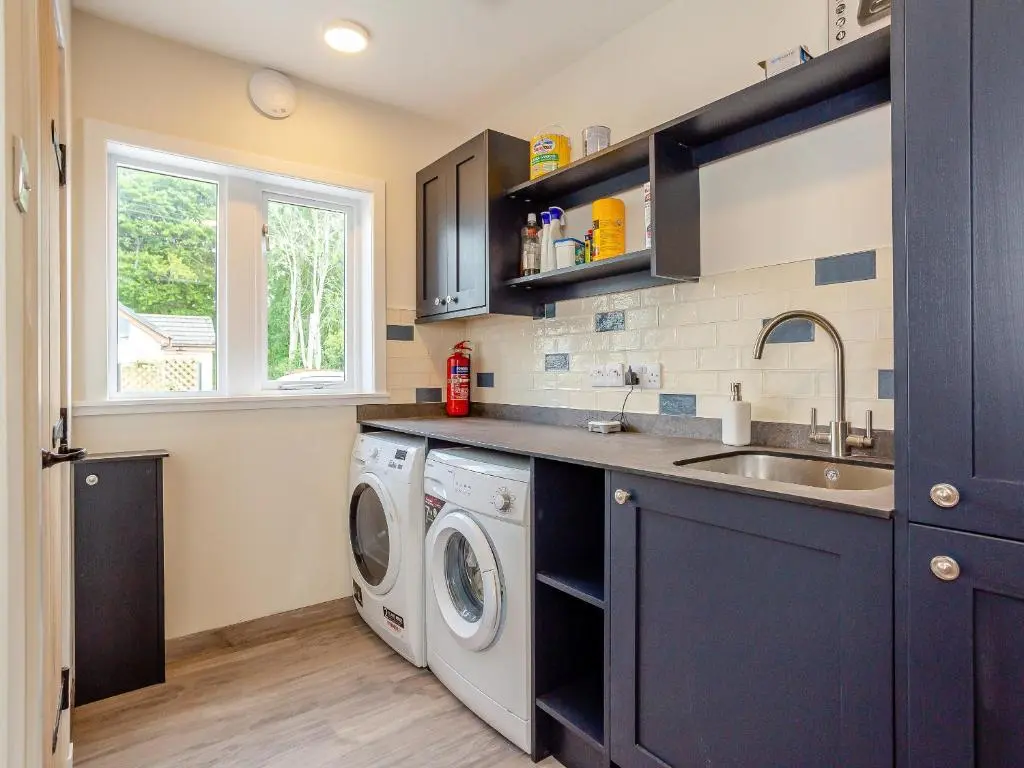 a kitchen with a washing machine and a sink at Woodford - Cottage in Boat of Garten