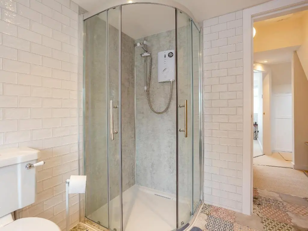 a shower with a glass door in a bathroom at Woodford - Cottage in Boat of Garten