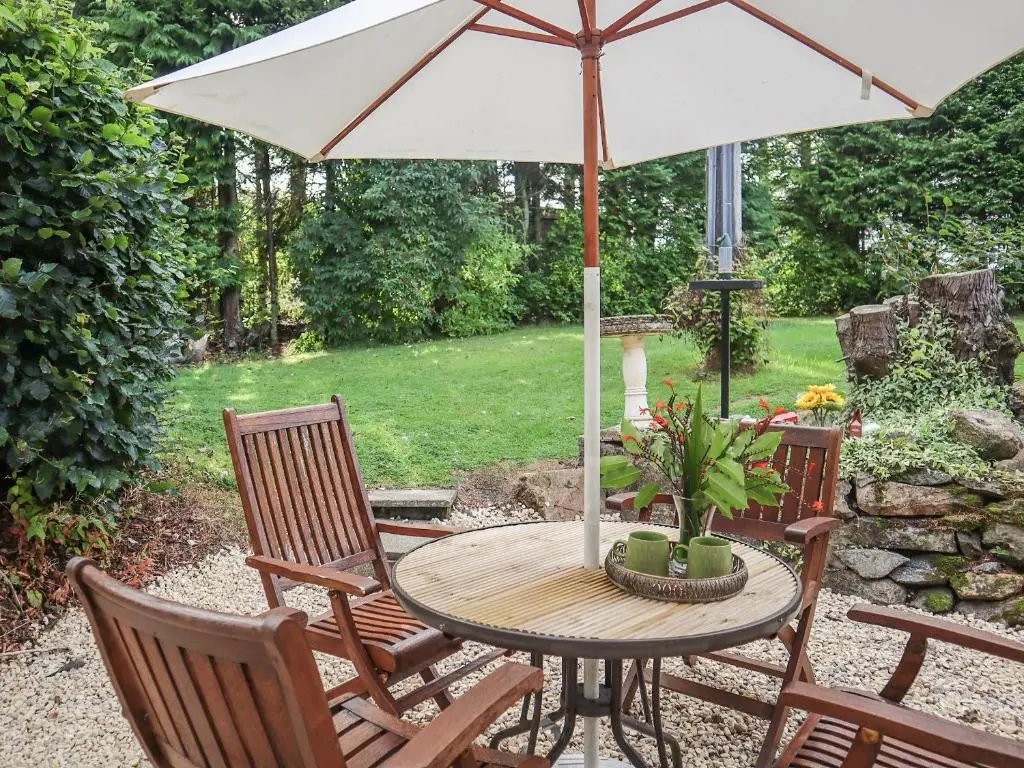 a table with an umbrella and three chairs at Elizabeth Lodge - Cottage in Alford