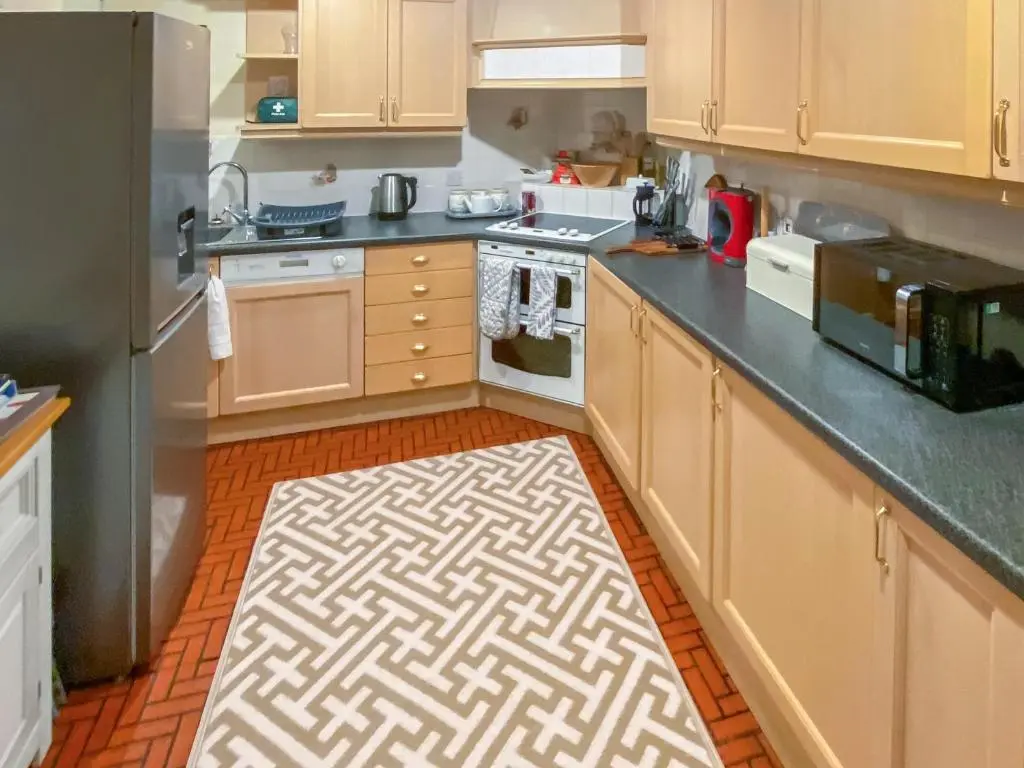 a kitchen with wooden cabinets and a kitchen rug on the floor at Elizabeth Lodge - Cottage in Alford