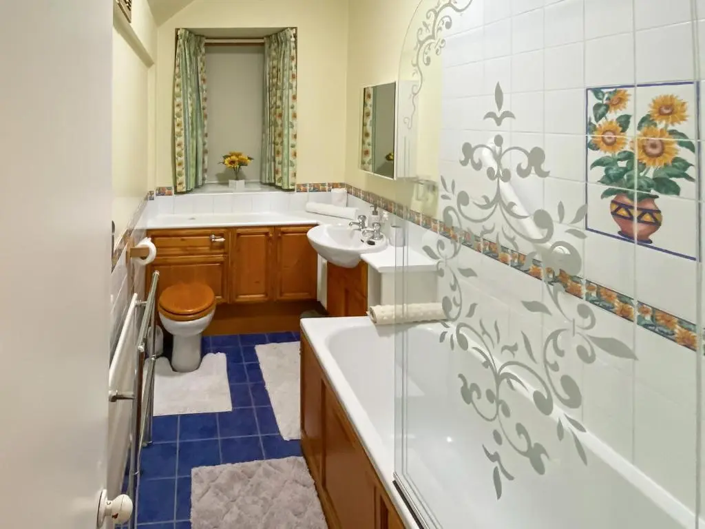 a bathroom with a tub and a sink and a toilet at Elizabeth Lodge - Cottage in Alford