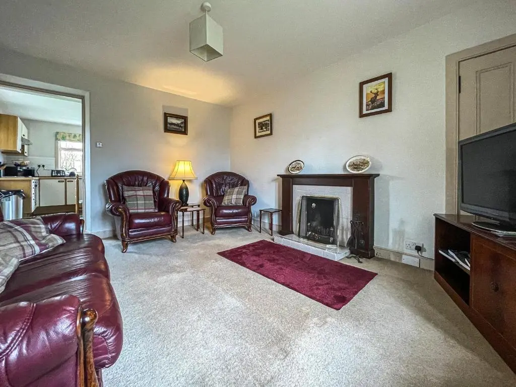 a living room with a couch and a fireplace at Milton Cottages in Invercassley